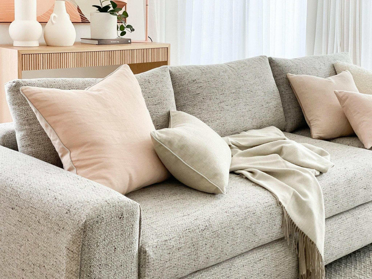 norsuHOME sofa beige fabric with soft cushions and a cozy throw in a stylish living room setting