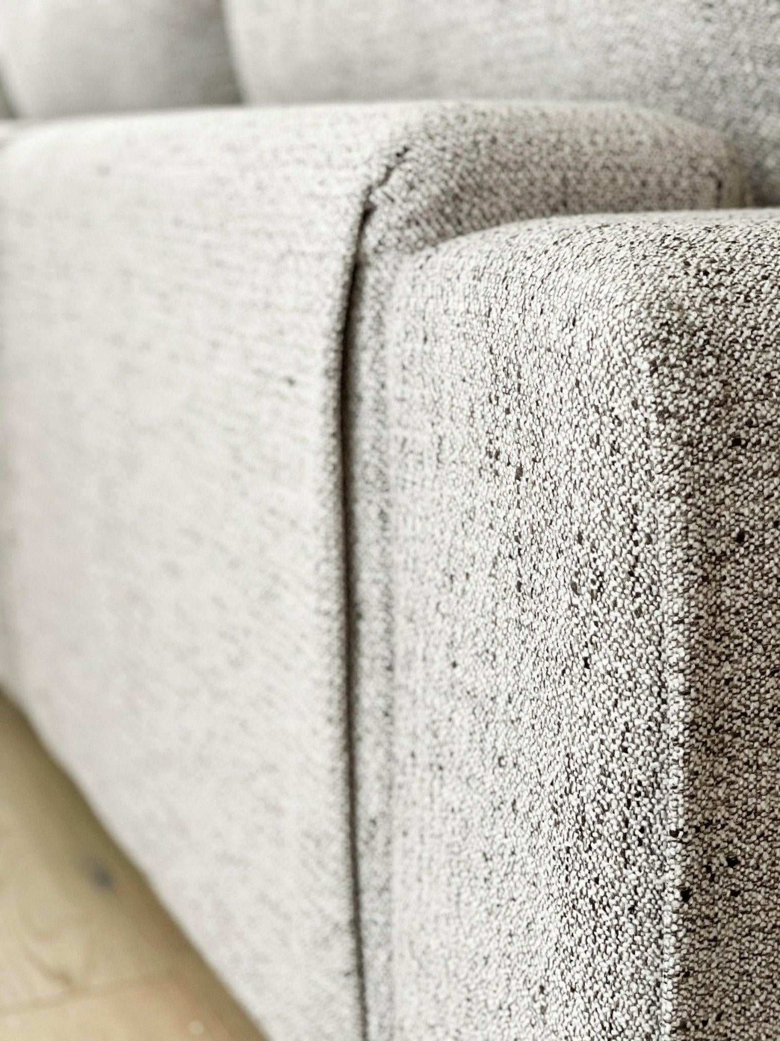 Close-up of textured light grey fabric on norsuHOME sofa armrest, highlighting durability and design quality