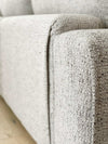 Close-up of textured light grey fabric on norsuHOME sofa armrest, highlighting durability and design quality