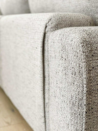 Close-up of textured light grey fabric on norsuHOME sofa armrest, highlighting durability and design quality