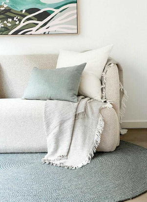norsu Studio Washable Cushion in duck egg on beige sofa with white cushion and textured throw in modern living room