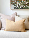 Norsu Studio washable honeycomb cushion in warm honey color on sofa with neutral pillows and wall art.