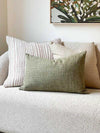 norsu Studio Washable Cushion in olive on sofa with textured beige and striped cushions