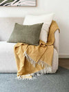 norsu Studio Washable Cushion in olive on sofa with yellow throw blanket