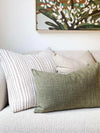 norsu Studio Washable Cushion in olive on sofa with decorative pillows and wall art