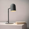 Minimalist charcoal Pia desk lamp with a cylindrical shade on a round base, ideal for modern desks or bedroom use
