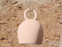 POTT Lighting Calo Pendant in salmon color with bell shape, handmade ceramic, hanging light fixture against rustic stone background
