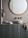 Robert Gordon Clay 340 Dish hand basin in sand color, round dish shape with high sides, installed on dark wood vanity under a round wooden framed mirror in a modern bathroom setting