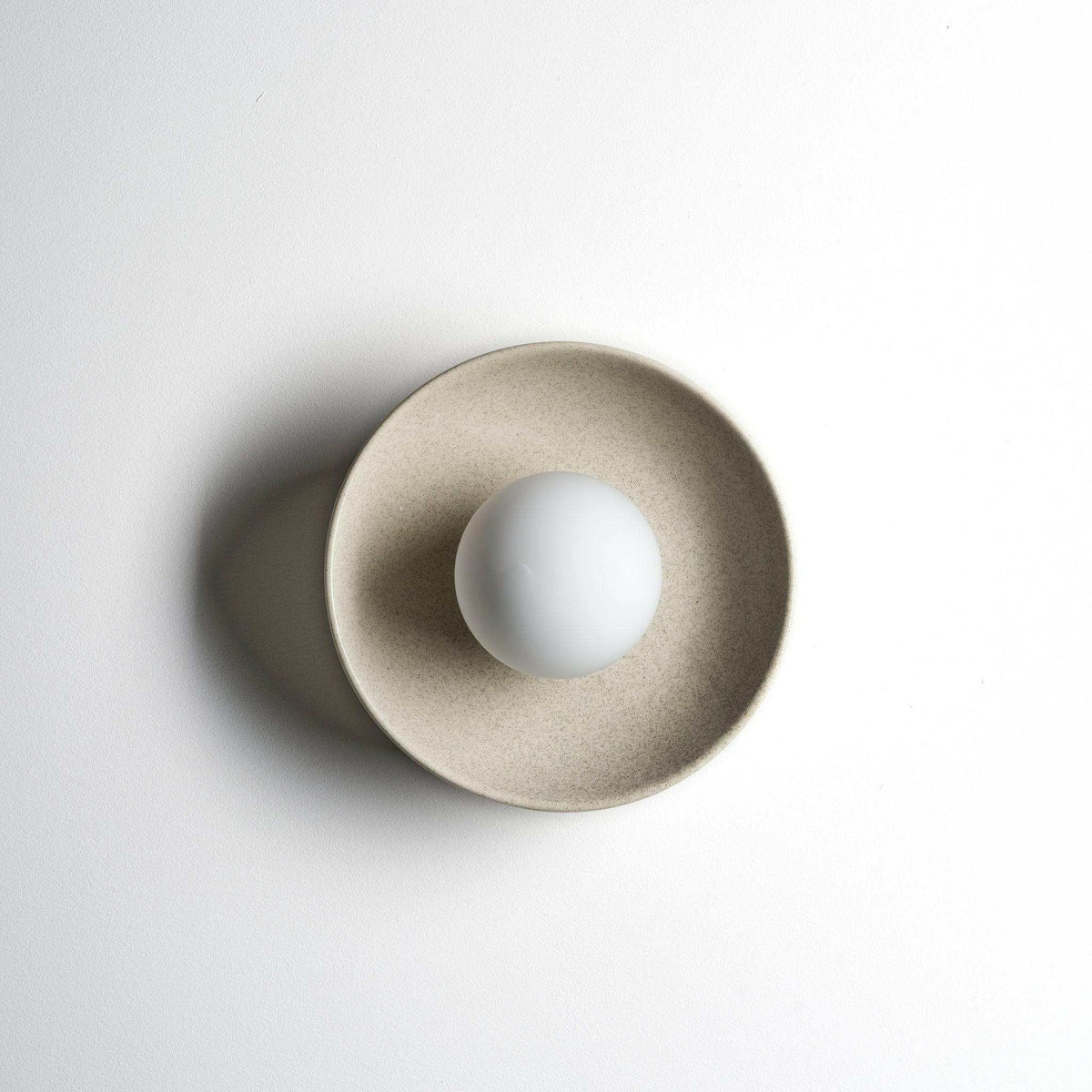 Robert Gordon ceramic dish wall sconce in poppyseed with round white globe light
