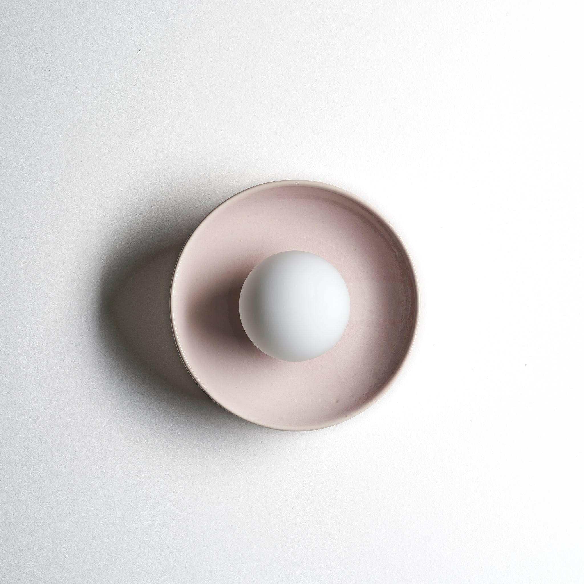 Robert Gordon Dish Wall Sconce in rose quartz ceramic with a round white bulb and minimalist design