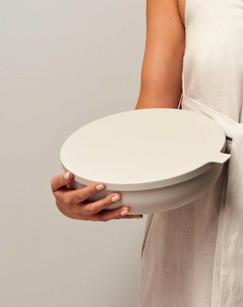Person holding a smoke-colored Styleware Nesting Bowl with a snap-tight lid from the Nesting Bowls Collection.