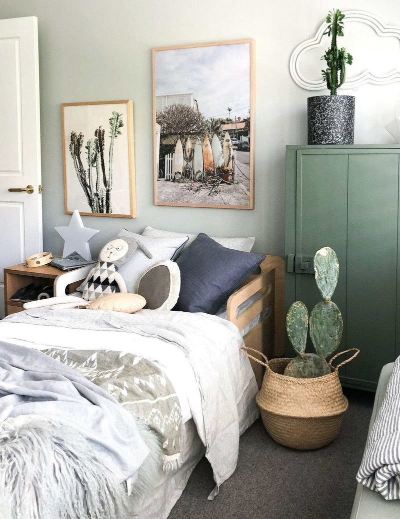 Summer Break Surfboard photographic wall art print in wooden frame displayed in a cozy bedroom with cactus plants and soft bedding