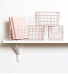 Set of three blush wire baskets designed for locker storage, including one large and two small baskets on a white shelf