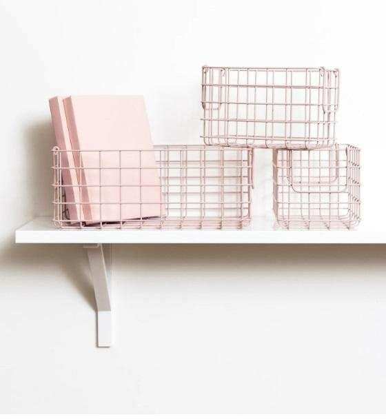 Set of three blush wire baskets designed for locker storage, including one large and two small baskets on a white shelf