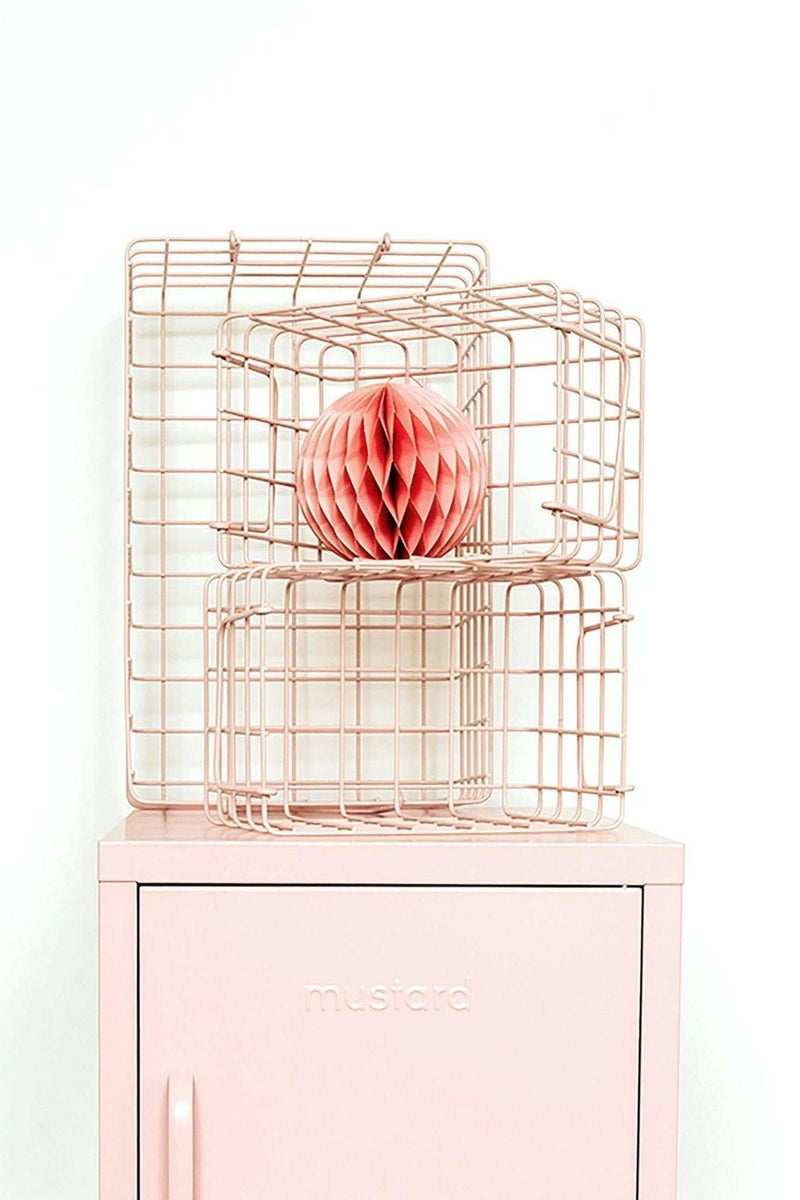 Set of blush pink wire baskets in varying sizes stacked on a pastel pink locker for organized storage