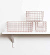 The Baskets in Blush set featuring one large and two small wire storage baskets on a white wall shelf