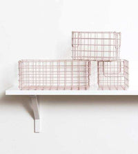 The Baskets in Blush set featuring one large and two small wire storage baskets on a white wall shelf
