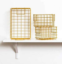 Set of mustard baskets with one large rectangular and two smaller square wireframe storage baskets on a white shelf