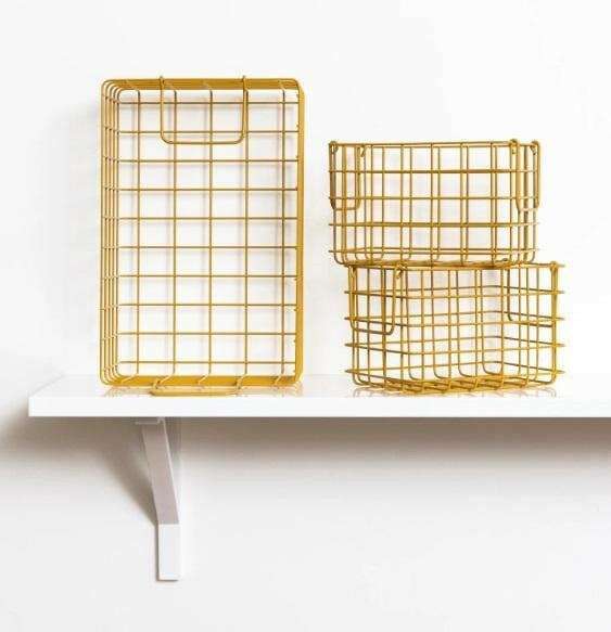Set of mustard baskets with one large rectangular and two smaller square wireframe storage baskets on a white shelf