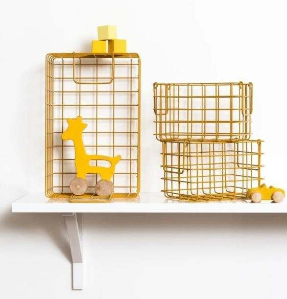 Set of three mustard baskets including one large and two small wire storage baskets on a white shelf with yellow wooden toys