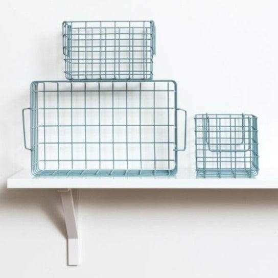 Set of ocean baskets including one large and two small wire storage baskets on a white shelf for organizing locker space