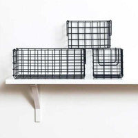 Set of three slate-colored wire baskets, one large rectangular and two smaller square, displayed on a white wall shelf for versatile storage.