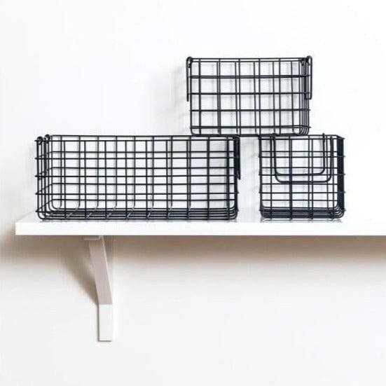 Set of three slate-colored wire baskets, one large rectangular and two smaller square, displayed on a white wall shelf for versatile storage.