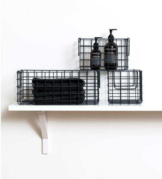 Set of three slate-colored metal storage baskets, including one large and two smaller baskets, displayed on a white shelf holding toiletries and towels