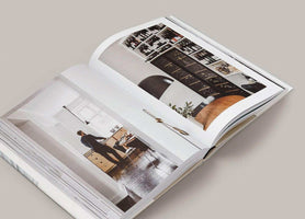 Open copy of The Kinfolk Home book displaying interior design photographs and lifestyle scenes