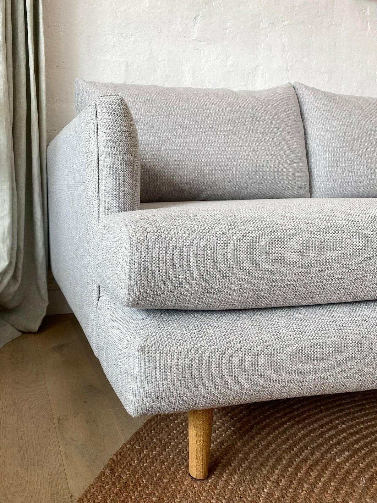 Custom Norsu Sofa 2.5 seater in Wells Driftwood fabric with wooden legs on hardwood floor near curtains