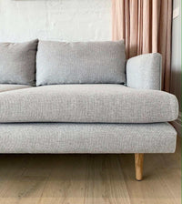 Custom Norsu Sofa 2.5 seater in Wells Driftwood fabric with wooden legs in a modern living room setting