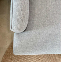 Close-up of Custom Norsu Sofa 2.5 seater armrest and cushion in Wells Driftwood fabric on woven rug.