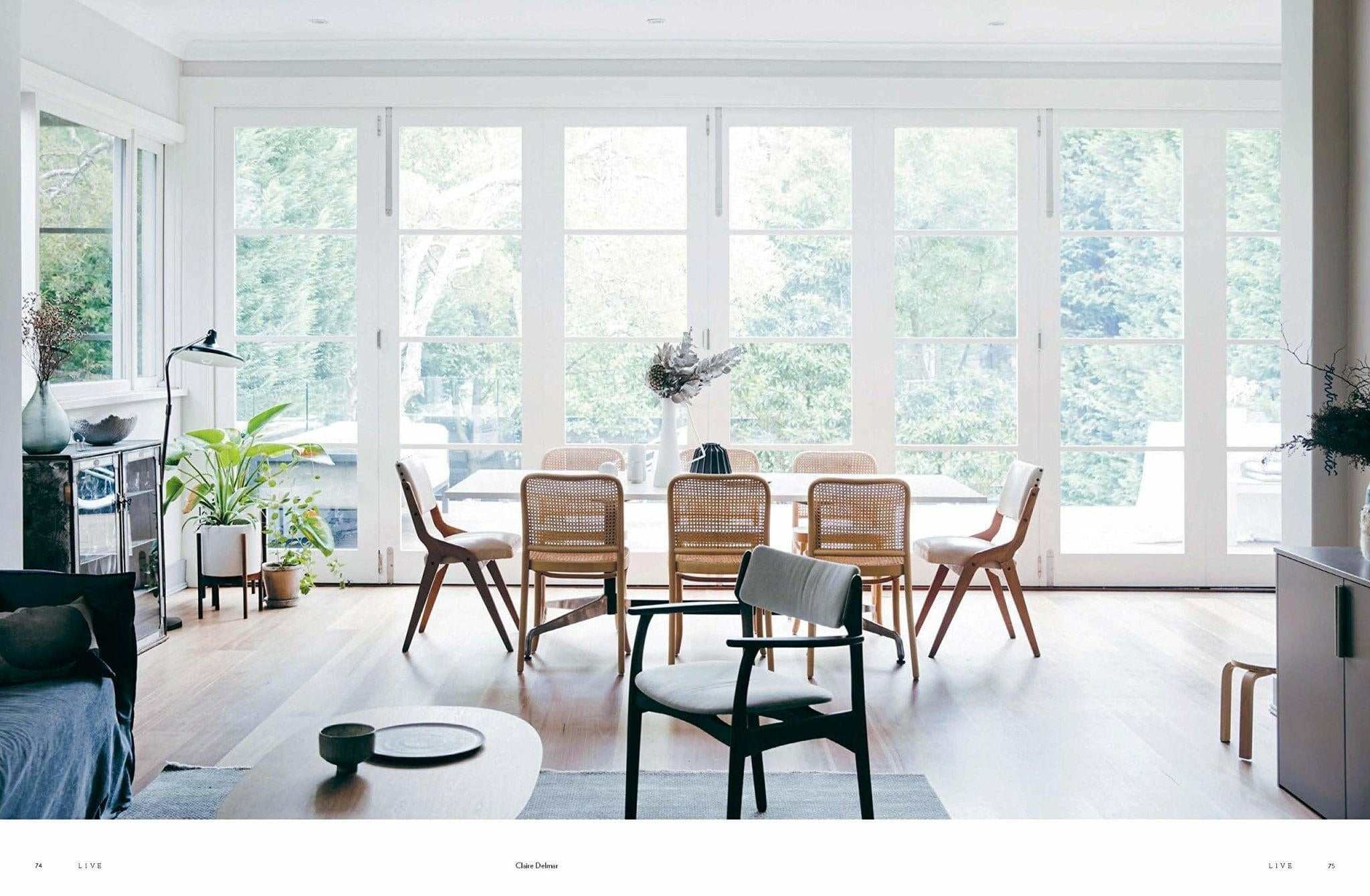Bright minimalist dining room with natural wood furniture and large windows overlooking greenery, illustrating simple living and authentic home design from 