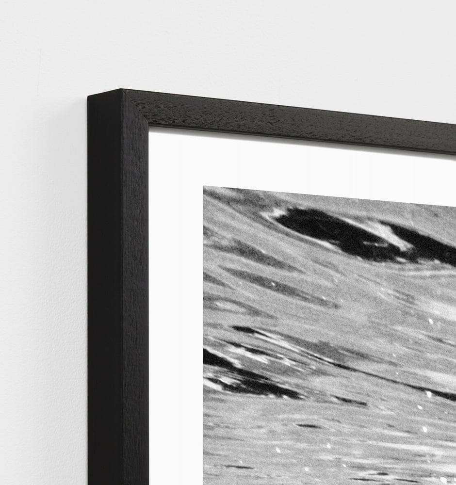 Close-up of black framed Middle of Nowhere Tropical Swim photographic print with abstract water design.