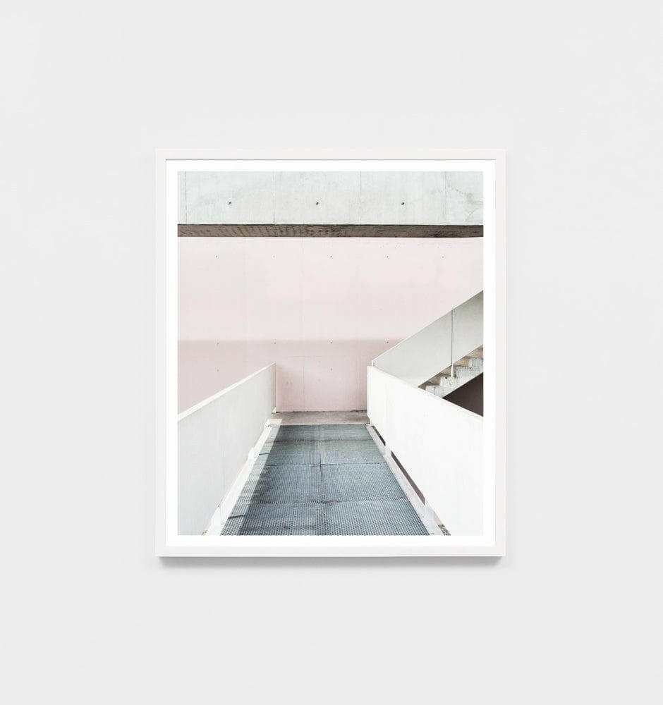 Minimalist framed photographic print titled Middle Of Nowhere 'Walkway' featuring a modern walkway in soft pink and white tones with a white frame.