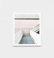 Minimalist framed photographic print titled Middle Of Nowhere 'Walkway' featuring a modern walkway in soft pink and white tones with a white frame.